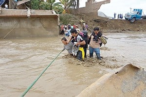 People cling to a rope and each other to cross floodwaters in La Rinconada, a town in the Puno region of Peru, in the Andes.